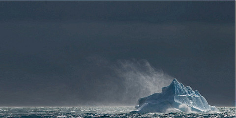 Wind blows over iceberg in ocean